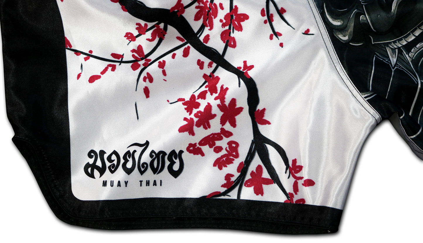 Close-up of the Cherry Blossom Samurai Muay Thai Shorts side detail, featuring sakura blossoms and traditional Muay Thai text, handcrafted in Thailand.