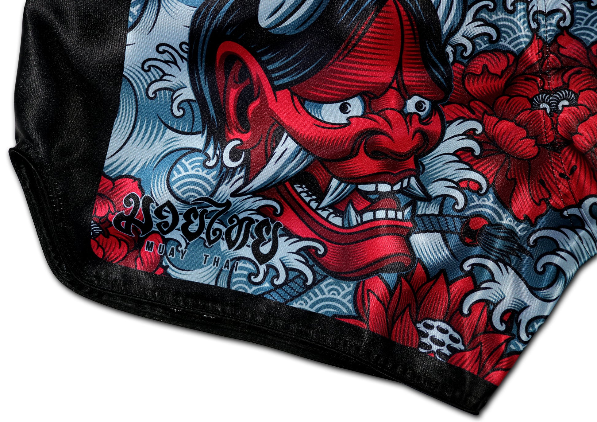 Detail picture of Devil's Koi Muay Thai Boxing Shorts showing the red Oni demon mask and intricate floral design, with "Muay Thai" text. Hand-made in Thailand.