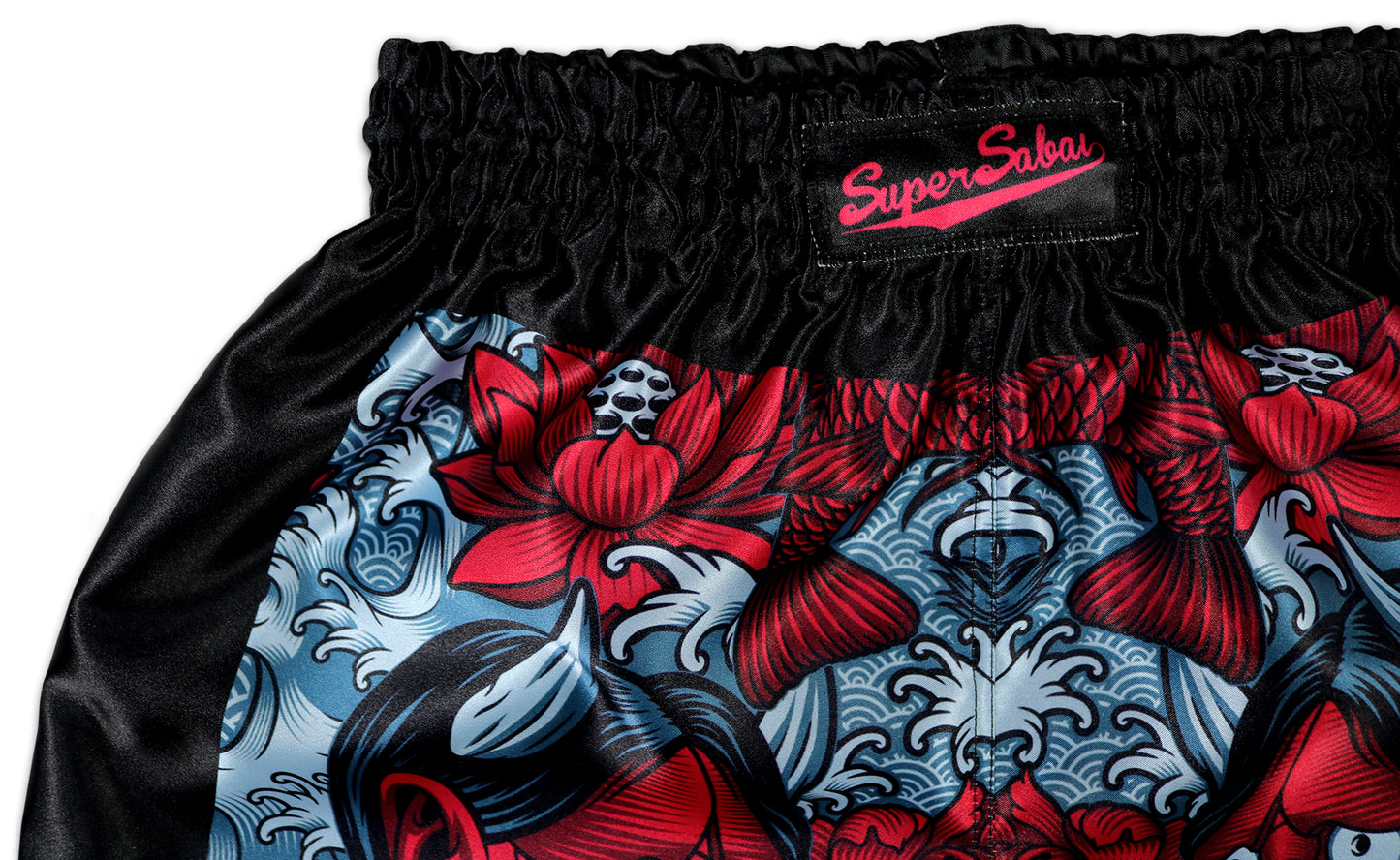 Close-up view of the waistband and design details on Devil's Koi Muay Thai Boxing Shorts, showing the Super Sabai brand label, red Oni demon mask, and floral patterns. Hand-made in Thailand.