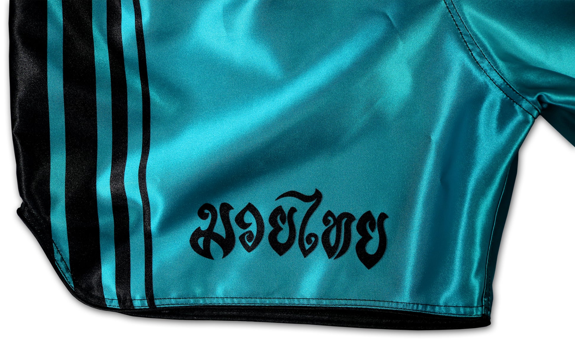 Close-up of the right leg of turquoise Muay Thai shorts, featuring black side stripes and Thai letters in black 