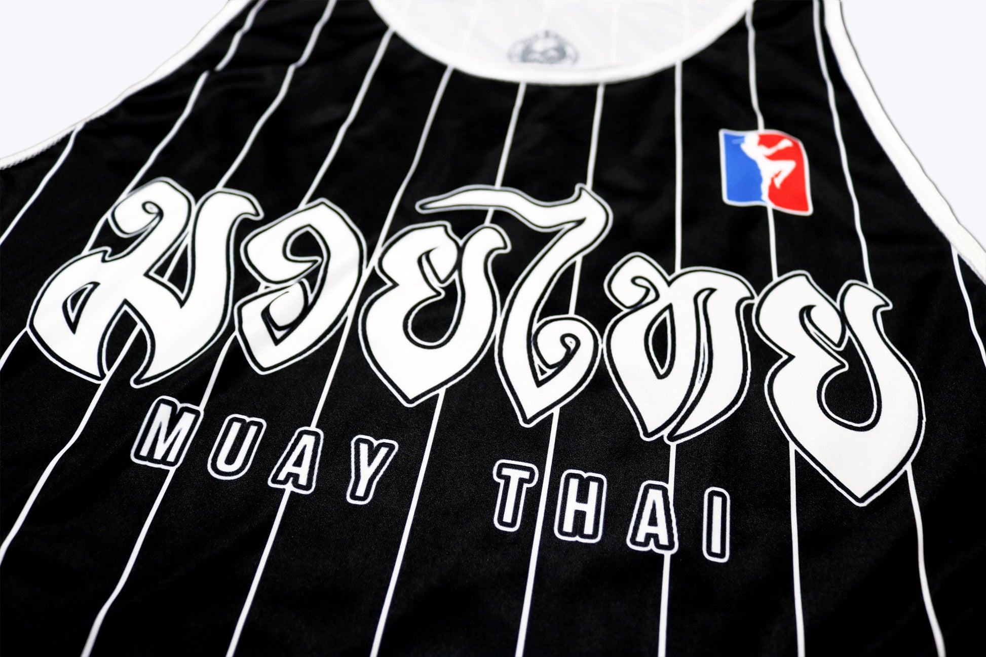 closeup of a black muay thai boxing tank top with classic white stripes showing a big muay thai lettering on the chest