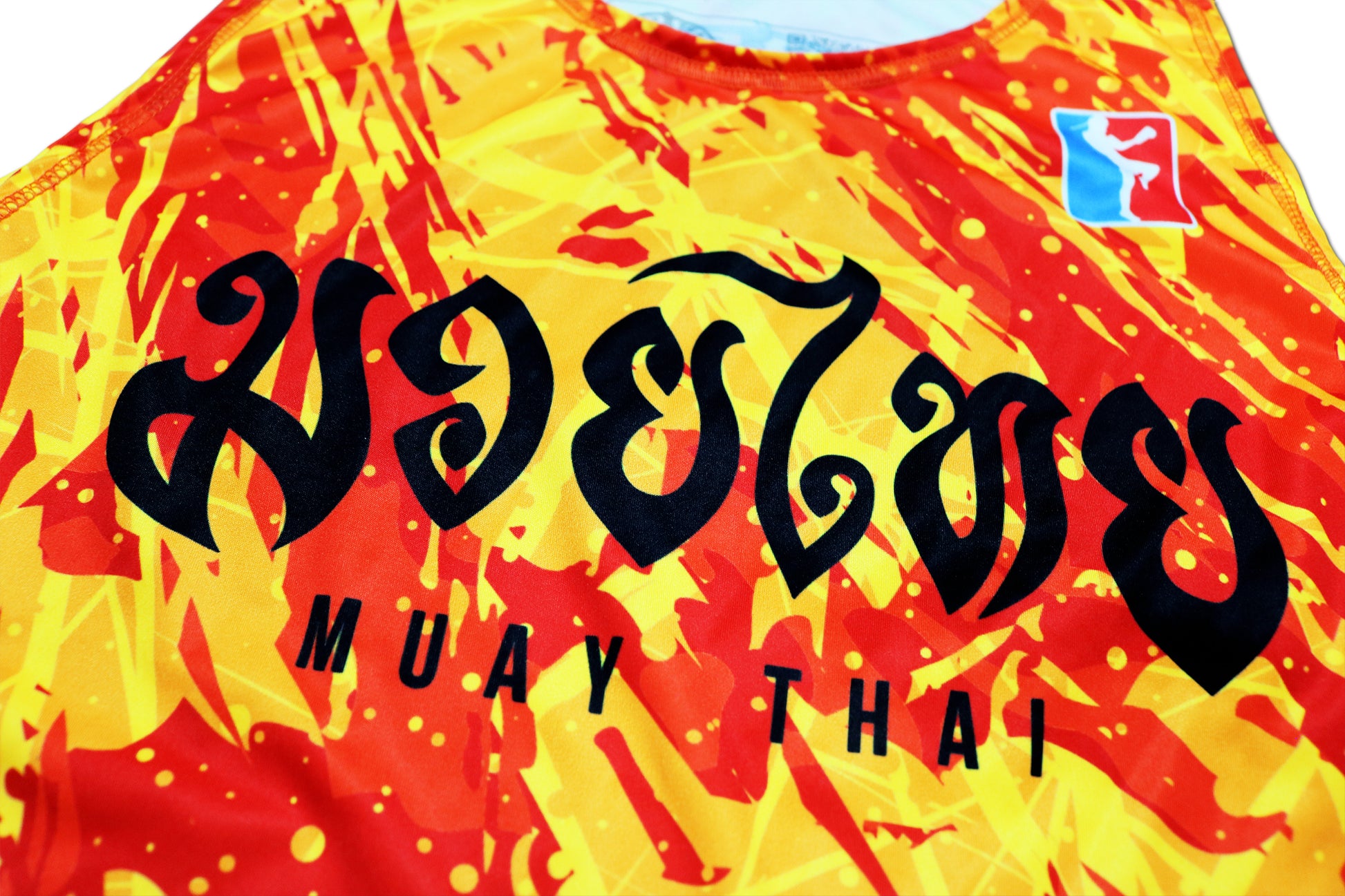 Close-up view of the brand new LAVA Muay Thai tank top, showcasing the vibrant red and yellow design with bold black 'Muay Thai' text 