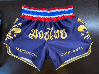 custom made muay thai shorts with blue / purble body and golden font and logos. thai flag waist